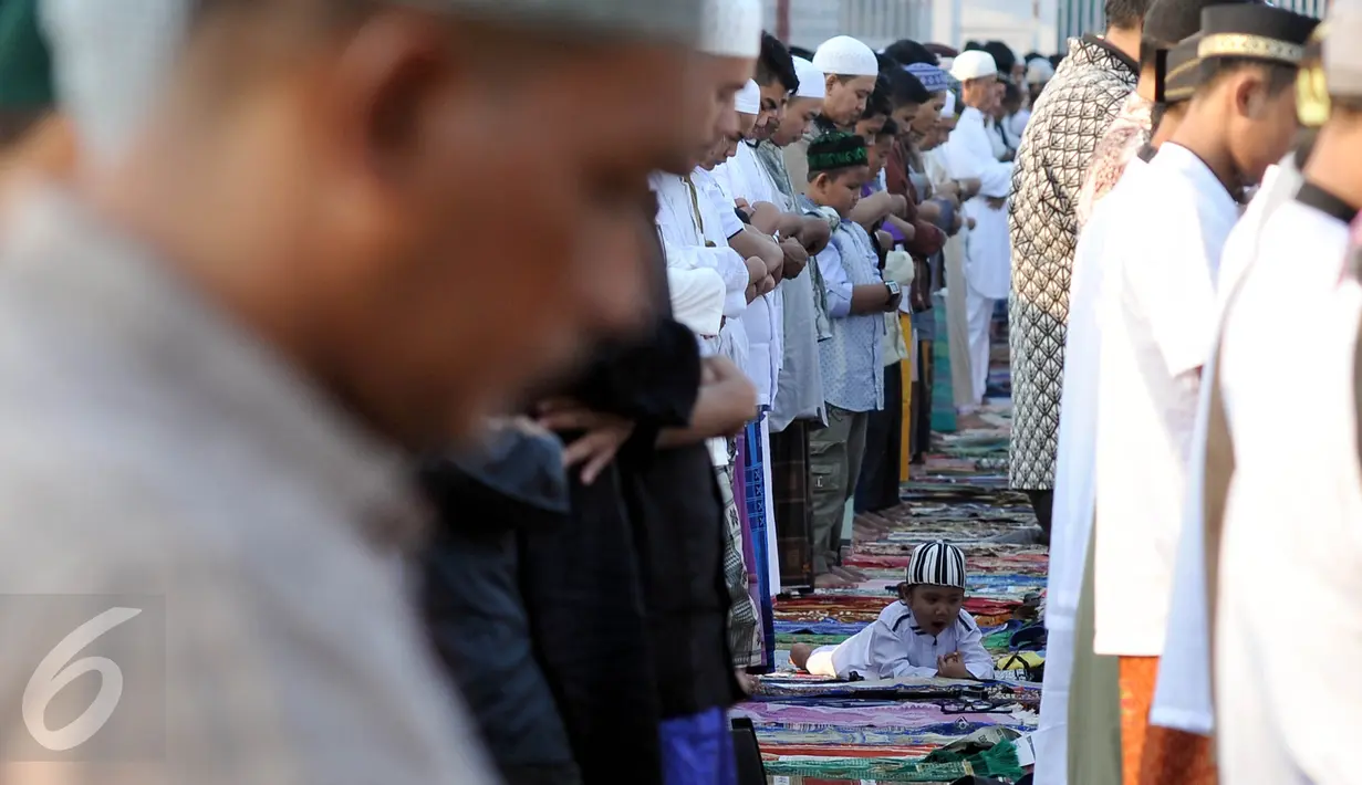 Seorang anak di antara umat muslim yang tengah melaksanakan salat Idul Fitri di Pelabuhan Sunda Kelapa, Jakarta, Rabu (6/7). Umat muslim seluruh dunia merayakan Lebaran 1437 H setelah melaksanakan ibadah puasa selama satu bulan. (Liputan6.com/Johan Tallo)