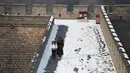 Dua wisatawan berjalan usai hujan salju mengguyur Tembok Besar China di utara Beijing (6/1/2020). Awal tahun 2020, musim dingin turun menyelimuti bagian utara Beijing yang mengakibatkan lokasi wisata yang menjadi salah satu keajaiban dunia tertutup salju. (AFP/Greg Baker)