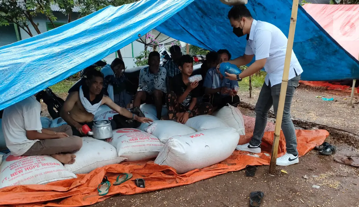 Warga korban gempa saat menerima bantuan di tenda pengungsian Pasaman Barat, Sumatera Barat, Jumat (26/2/2022). BRI terus bersinergi dengan pemerintah setempat dan Badan Usaha Milik Negara (BUMN) untuk bahu membahu membantu meringankan beban masyarakat yang terdampak gempa.(Liputan6.com/HO/CSR BRI)