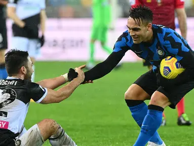 Pemain Inter Milan, Lautaro Martinez (kanan) saat membantu pemain Udinese Tolgay Arslan dalam laga lanjutan Liga Itali 2020/2021 di Friuli stadium, Minggu (24/1/2021) dini hari. (Foto: AFP/Vincenzo Pinto)
