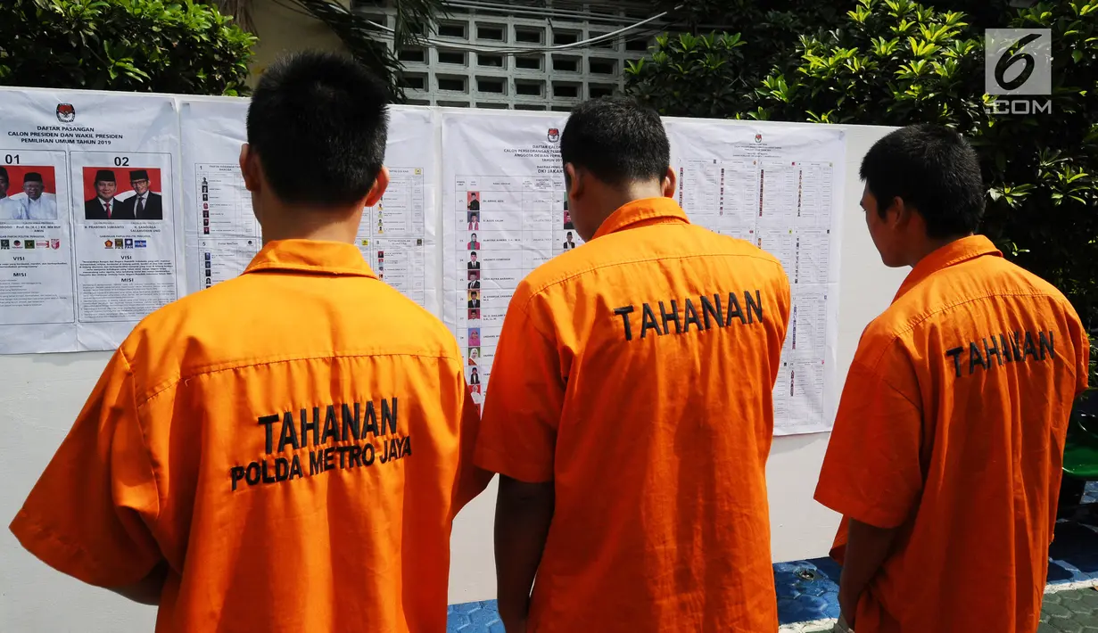 Tahanan melihat informasi kandidat capres-cawapres dan para caleg sebelum mencoblos di TPS 15 Rutan Polda Metro Jaya, Jakarta, Rabu (17/4). Para tahanan Rutan Polda Metro Jaya melakukan pencoblosan di dua lokasi yakni TPS 14 dan TPS 15. (Liputan6.com/Herman Zakharia)