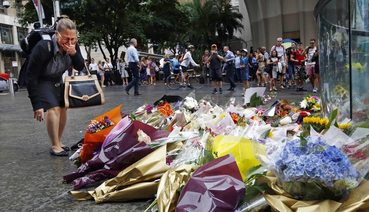 Seorang wanita bereaksi usai meletakkan bunga sebagai penghormatan bagi korban penyanderaan di Kafe Lindt, Sidney, Australia (16/12/2014). Tiga orang tewas dan empat terluka dalam penyanderaan yang terjadi selama lebih dari 16 jam. (REUTERS/Jason Reed)