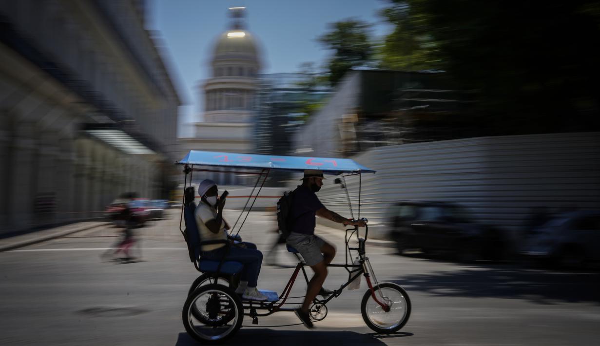 <p>Seorang penumpang mengendarai taksi sepeda melewati Capitol di Havana, Kuba, Selasa (17/5/2022). Pemerintahan Presiden AS, Joe Biden mengumumkan akan melonggarkan pembatasan atas pengetatan yang diberlakukan selama pemerintahan Donald Trump terhadap Kuba dan mencabut batas saat ini $1.000 per kuartal yang dapat dikirim imigran kepada anggota keluarga yang masih tinggal di pulau itu. (AP Photo/Ramon Espinosa)</p>
