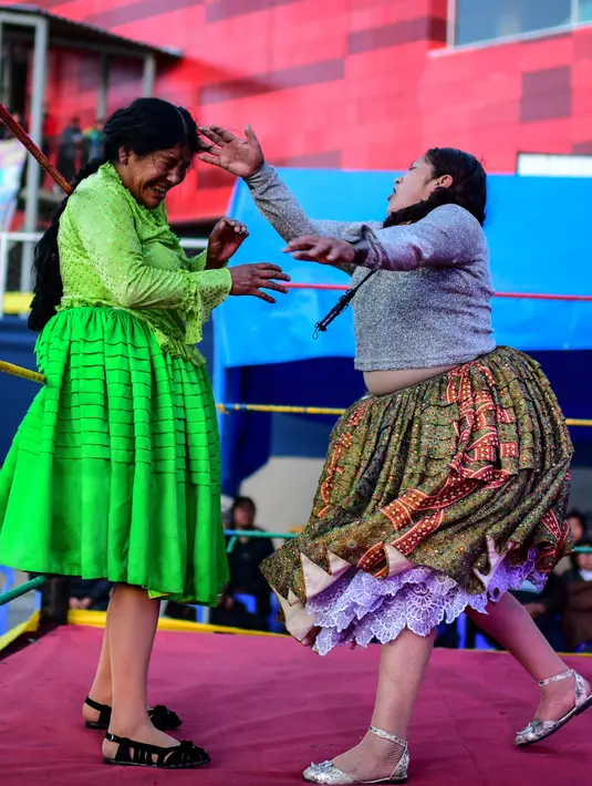 Pegulat Bolivia Ana Luisa Yujra (kiri), bertarung dengan lawannya, Lidia Flores, di atas ring gulat di El Alto, pada 24 November 2019. Di Bolivia ada sebuah atraksi gulat yang diperankan perempuan dengan menggunakan busana khas warga Bolivia. (Ronaldo SCHEMIDT / AFP)