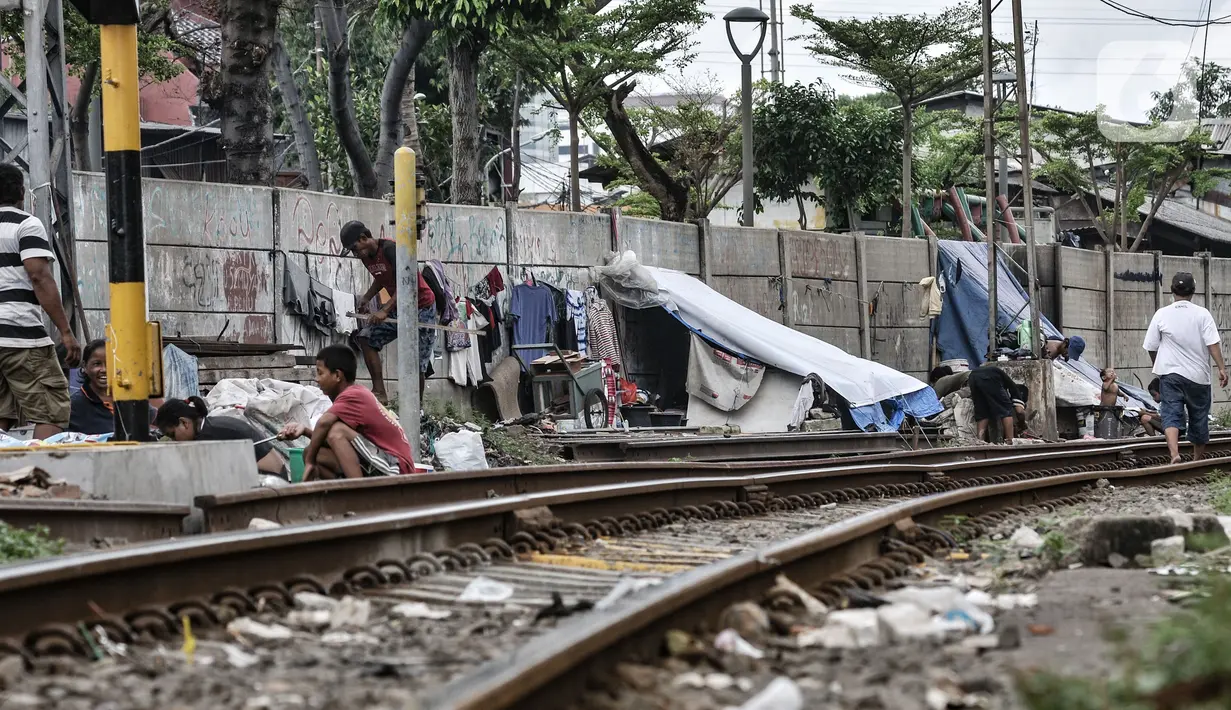 Sejumlah tunawisma beraktivitas di dekat gubuknya yang berada di bantaran rel kereta api kawasan Senen, Jakarta, Minggu (14/2/2021). Setelah sempat ditertibkan, puluhan bangunan semipermanen yang beratapkan terpal dan beralas kardus milik tunawisma kembali menjamur. (merdeka.com/Iqbal S. Nugroho)