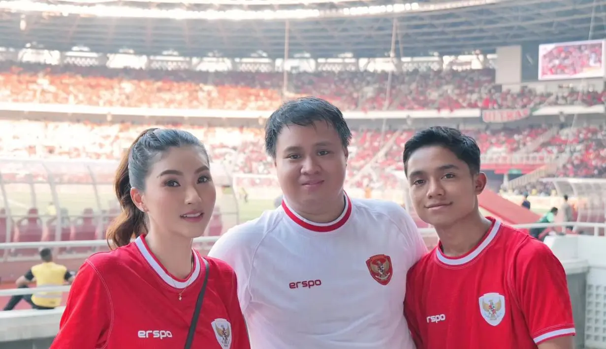Sarwendah turut nonton pertandingan di GBK bersama sang putra, Bertrand. Ia juga mengenakan jersey timnas berwarna merah yang dipadukan long pants putih dan sling bag hitam.