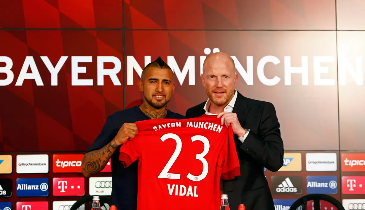 Gelandang Cile, Arturo Vidal, bersama Matthias Sammer berpose dengan jersey Bayern Munchen di Allianz Arena, Munchen, Jerman (28/7/2015). Bayern Munchen resmi mengontrak Vidal dengan kontrak selama empat musim. (Reuters/Michaela Rehl)