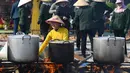 Seorang wanita sedang mengawasi panci mendidih berisi "Banh Chung" atau kue beras tradisional Vietnam untuk amal, menjelang Tahun Baru Imlek atau festival Tet di Pagoda Tam Chuc di provinsi Ha Nam (7/1/2023). Banh Chung adalah kelezatan khas Vietnam yang terbuat dari ketan, daging babi, dan kacang hijau yang dibungkus dengan daun pisang dan dimasak selama 10 jam. (AFP/Nhac Nguyen)