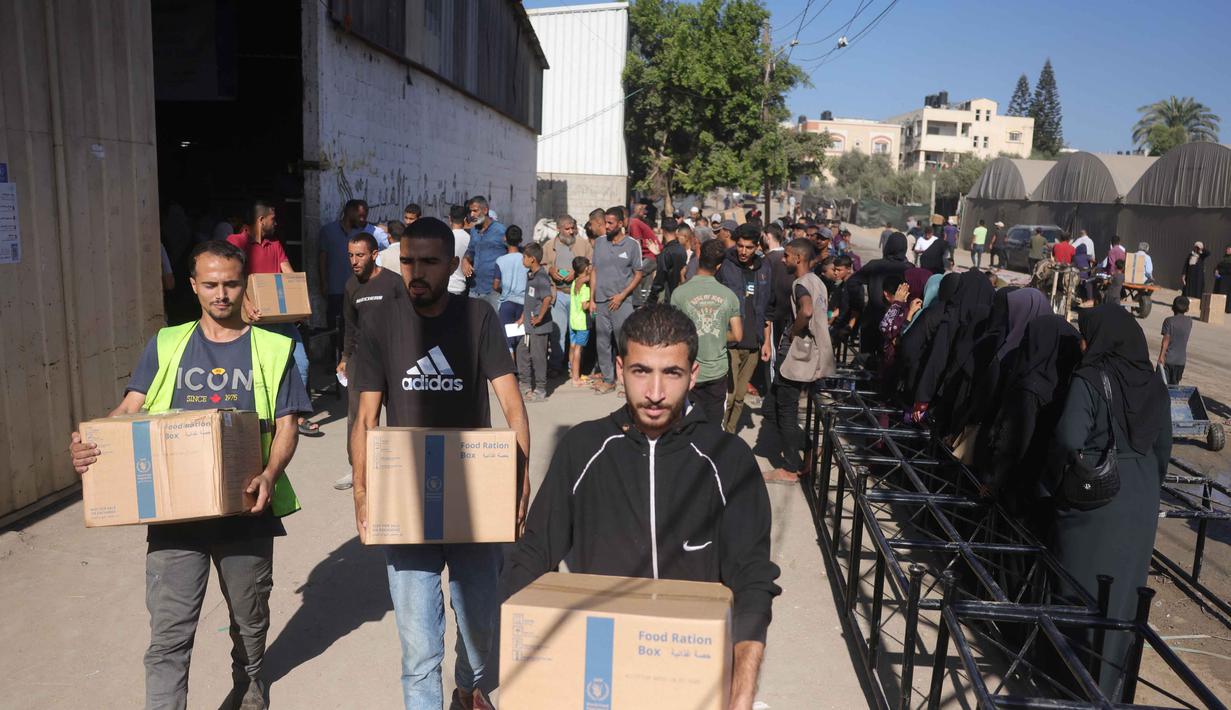 Warga Palestina mengangkat kotak bantuan dari Program Pangan Dunia (WFP) di pusat distribusi di desa Al-Zawayda, di tengah-tengah Jalur Gaza, pada 27 Oktober 2025. (BASHAR TALEB/AFP)