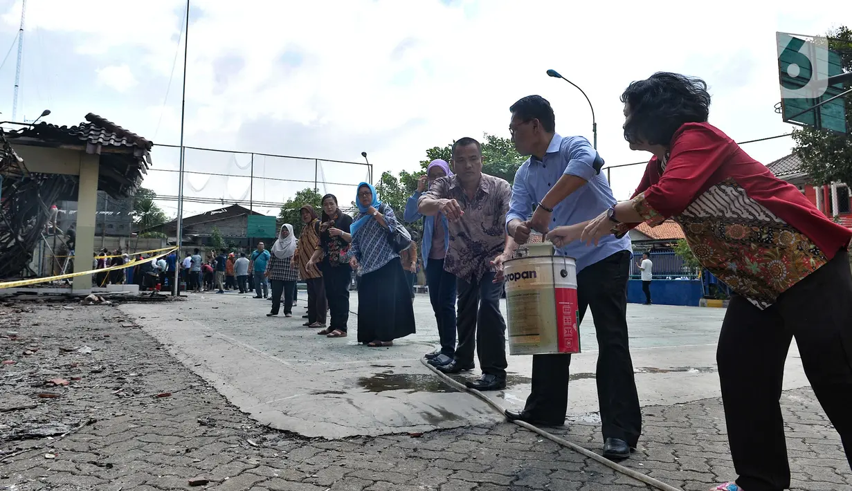 Sejumlah guru, pegawai, dan siswa bergotong royong saat berusaha memadamkan api yang kembali muncul di Gedung SMK Yadika 6, Jatiwaringin, Pondok Gede, Kota Bekasi, Jawa Barat, Selasa (19/11/2019). Kebakaran kembali terjadi di Gedung SMK Yadika 6 sekitar pukul 12.30 WIB. (merdeka.com/Iqbal Nugroho)