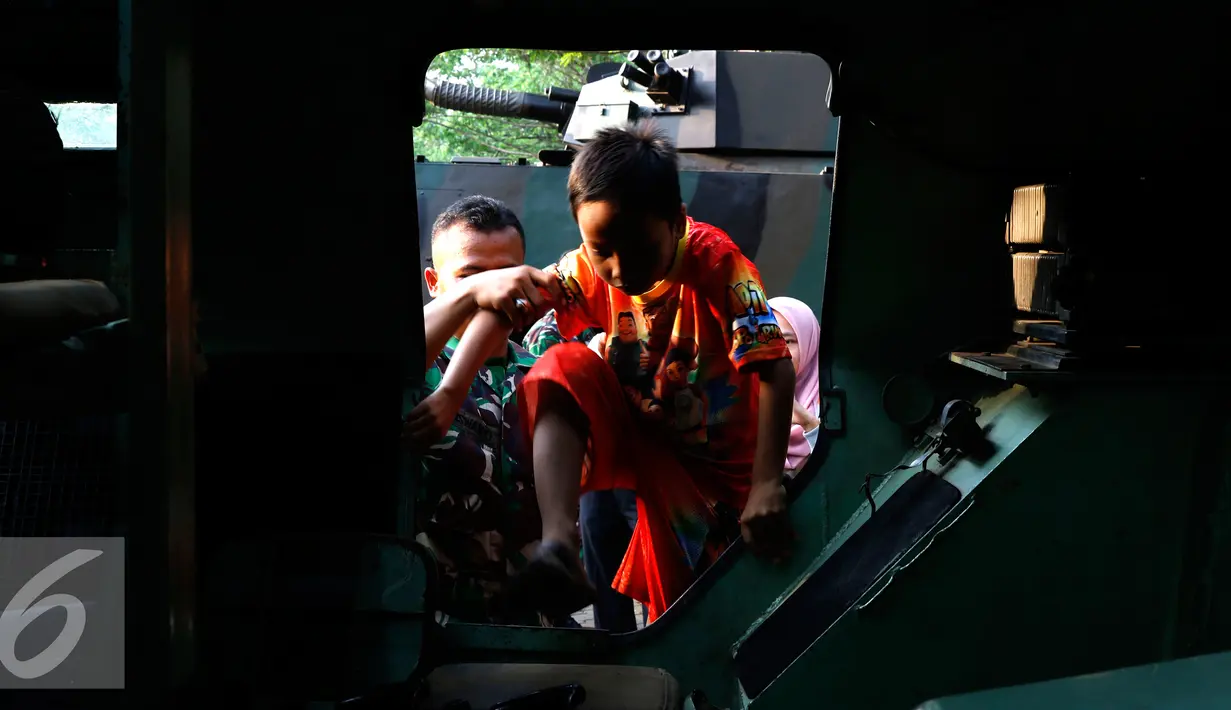 Anggota TNI membantu seorang anak menaiki Panser Anoa dalam pameran road to campus Alat Utama Sistem Persenjataan (Alutsista) di kawasan Boulevard Universitas Indonesia, Depok, Jawa Barat, Kamis (27/8/2015). (Liputan6.com/Yoppy Renato)