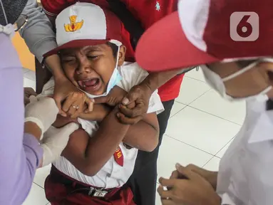 Seorang murid ketakutan saat mendapatkan  vaksin tetanus di Madrasah Ibtidaiyah (MI) Negeri 7, Cengkareng Timur, Jakarta Barat, Selasa (7/12/2021). Sebanyak 1.600 murid SD dan MI di wilayah Kelurahan Cengkareng Timur menjalani suntik imunisasi TD dan TDaP. (Liputan6.com/Johan Tallo)