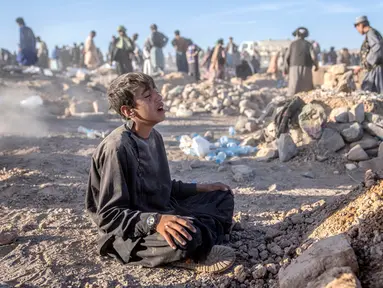 Seorang anak laki-laki berduka di samping makam adik laki-lakinya yang meninggal akibat gempa bumi di Distrik Zenda Jan, Provinsi Herat, sebelah barat Afghanistan, Senin (9/10/2023). Gempa mematikan yang terjadi pada Sabtu lalu menewaskan dan melukai ribuan orang serta menghancurkan rumah-rumah yang tak terhitung jumlahnya. (AP Photo/Ebrahim Noroozi)