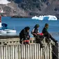Sejumlah warga duduk di dermaga Desa Kulusuk, Kota Sermersooq, Greenland, Denmark, 16 Agustus 2019. Belakangan, angka pengangguran di Desa Kulusuk cukup tinggi dan populasi penduduknya turun. (Jonathan NACKSTRAND/AFP)