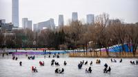 Orang-orang menggunakan kursi yang dimodifikasi untuk meluncur melintasi es dalam kolam saat pekan liburan Tahun Baru Imlek di taman umum selama pekan liburan Tahun Baru Imlek di Beijing, China, Kamis (26/1/2023). (AP Photo/Mark Schiefelbein)