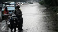 Warga saat mendorong motornya yang mogok akibat genangan air dikawasan Kelapa Gading, Jakarta, Jumat (26/2/2016). Hujan deras yang mengguyur Ibukota membuat beberapa ruas jalanan tersendat. (Liputan6.com/Faizal Fanani)