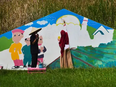 Seorang seniman lokal melukis mural di tengah sawah selama kegiatan The Art of Color Sensation 2019 di sebuah desa wisata Gampong Nusa, Lhoknga, provinsi Aceh, Minggu (16/6/2019). Kegiatan itu salah satunya meningkatkan daya tarik wisatawan untuk berkunjung ke Aceh. (CHAIDEER MAHYUDDIN/AFP)