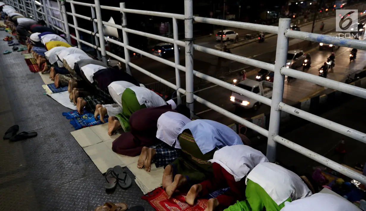 Jemaah melaksanakan salat tarawih di atas JPO akibat melubernya Musala Miftahul Jannah di Kawasan Pasar Gembrong, Jakarta, Kamis (17/5). (Liputan6.com/JohanTallo)
