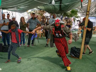 Rombongan badut Spanyol menghibur anak-anak Palestina di desa suku Bedouin, Tepi Barat yang diduduki, 22 September 2018. Atraksi ini dilakukan lantaran desa berpenduduk sekitar 180 orang itu akan digusur Israel pada Oktober mendatang. (AFP/ABBAS MOMANI)
