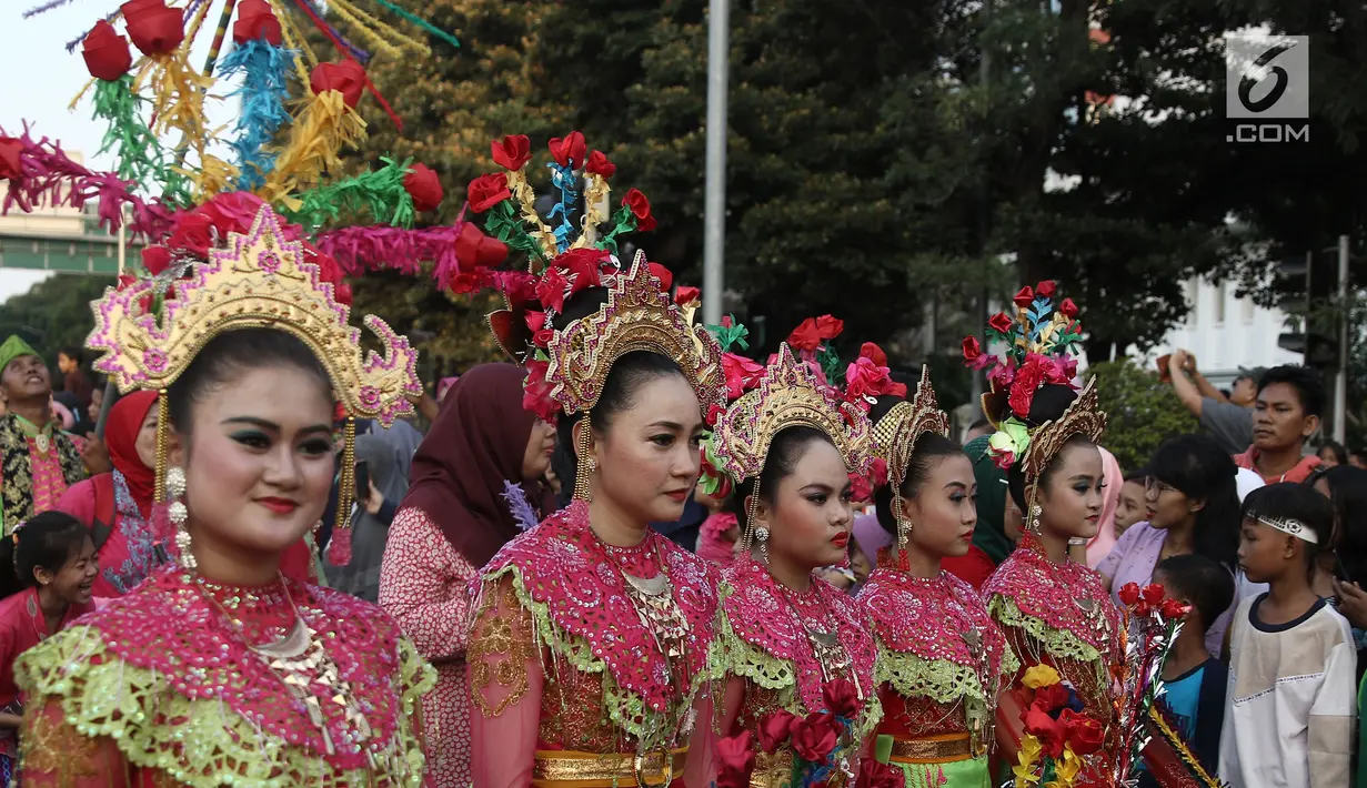 Peserta mengenakan busana tradisional saat memeriahkan Jakarnaval 2018 di Jalan Medan Merdeka Selatan, Jakarta, Minggu (8/7). Karnaval dimeriahkan oleh beragam atraksi dan pawai budaya Nusantara. (Liputan6.com/Herman Zakharia)