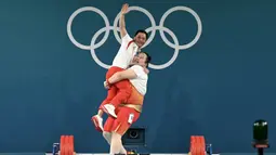 Lifter China, Li Wenwen mengagkat pelatihnya saat melakukan selebrasi setelah meraih medali emas cabang olahraga angkat besi +81kg putri Olimpiade Paris 2024 di South Paris Arena, Paris, Prancis, Sabtu (11/08/2024).  (AFP/Arun Sankar)