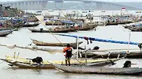 Seorang nelayan memindahkan perahunya melewati jajaran perahu, mendekati pantai perkampungan nelayan, tak jauh dari jembatan Suramadu, di Nambangan Kenjeran Surabaya. (Antara)