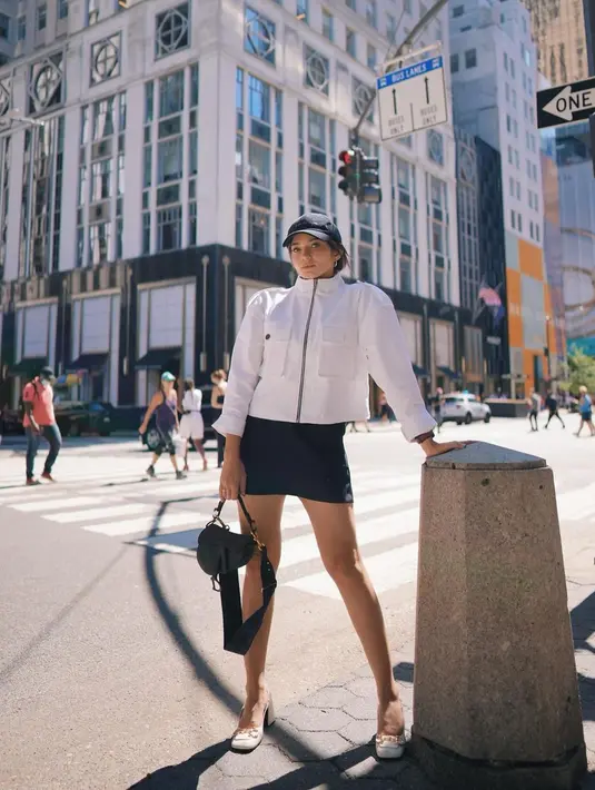 Gaya chic Enzy Storia saat berada di New York juga tak lepas dari sorotan netizen. Dirinya terlihat tampil dengan konsep monokrom menggunakan jaket putih serta rok hitam dengan topi, tas serta sepatu senada. (Liputan6.com/IG/@enzystoria)