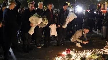 Grup band U2 Bono, Adam Clayton , Larry Mullen Jr  dan The Edge meletakkan karangan bunga di trotoar di depan gedung pertunjukan Bataclan Theatre, salah satu tempat serangan teroris di Paris, Perancis, Sabtu (14/11). (AFP PHOTO / FRANCK FIFE)