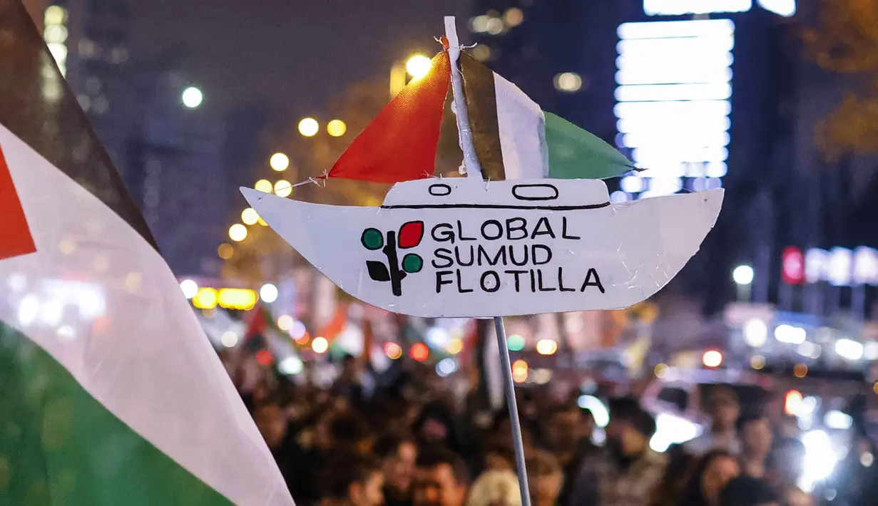 Seorang pengunjuk rasa memegang plakat penghormatan kepada Global Sumud Flotiila saat berunjuk rasa dalam solidaritas kepada warga Palestina dan mengutuk pencegatan armada oleh tentara Israel, di Istanbul, Turki pada 2 Oktober 2025. (KEMAL ASLAN/AFP)