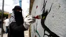 Seorang seniman melukis grafiti pada dinding di Ibu Kota Sanaa, Yaman, Kamis (15/3). Kegiatan ini  merupakan bentuk kampanye yang disebut 'Open Day of Art'. (Mohammed HUWAIS/AFP)