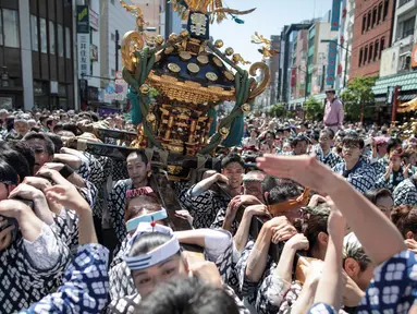 Para peserta membawa kuil portabel atau "Mikoshi" pada Festival Sanja Matsuri di luar kuil Sensoji, Tokyo, Minggu (20/5). Sanja Matsuri adalah festival tahunan di distrik Asakusa yang diadakan pada akhir pekan ketiga pada bulan Mei. (AFP/Behrouz MEHRI)