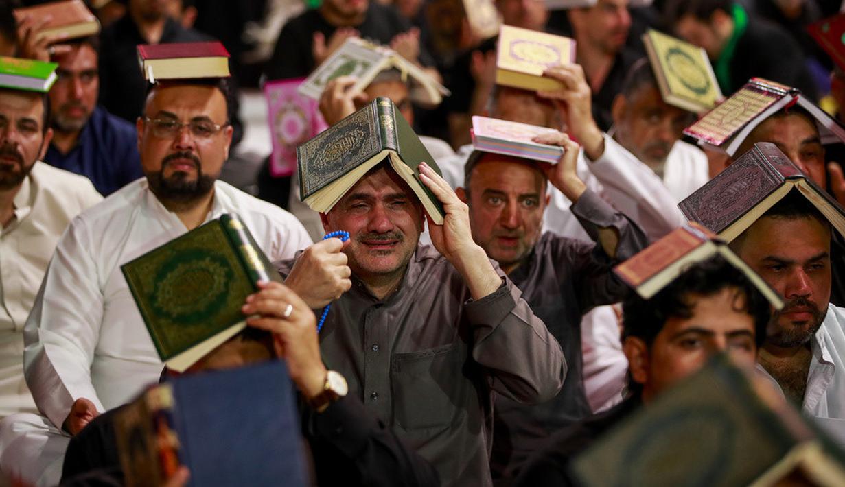 <p>Para pria Syiah menaruh mushaf Alquran di atas kepala mereka saat menghadiri sholat lailatulqadar pada bulan suci Ramadhan. (AP Photo/Anmar Khalil)</p>