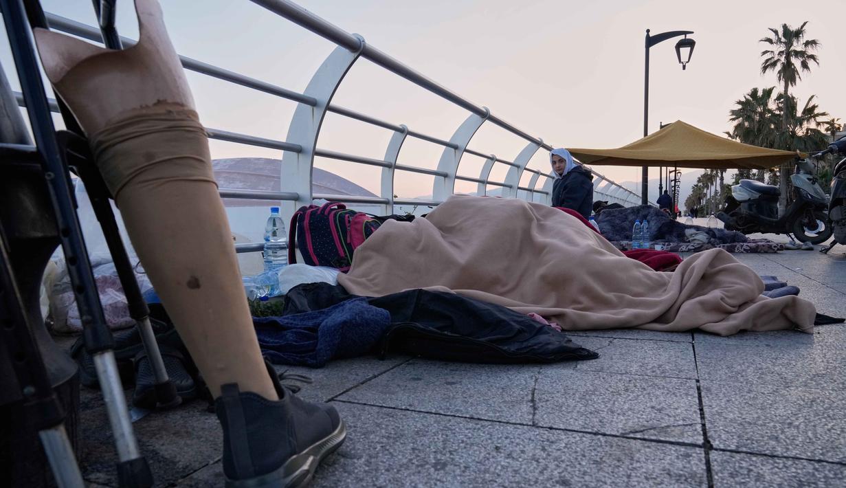 Perintah evakuasi memicu kepanikan luar biasa. Tampak dalam foto, para pengungsi yang melarikan diri dari serangan udara Israel di Dahiyeh, pinggiran selatan Beirut, tidur di tepi pantai Beirut, Lebanon, Jumat, 6 Maret 2026, dengan ditutupi selimut. (AP Photo/Hussein Malla)