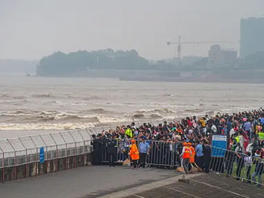 Warga menyaksikan gelombang pasang Sungai Qiantang dari pinggir sungai di Hangzhou, Zhejiang, China, 4 Oktober 2020. Gelombang pasang Sungai Qiantang yang terkenal dengan tinggi dan kecepatannya terjadi bertepatan dengan libur Hari Nasional dan Festival Pertengahan Musim Gugur. (Xinhua/Jiang Han)
