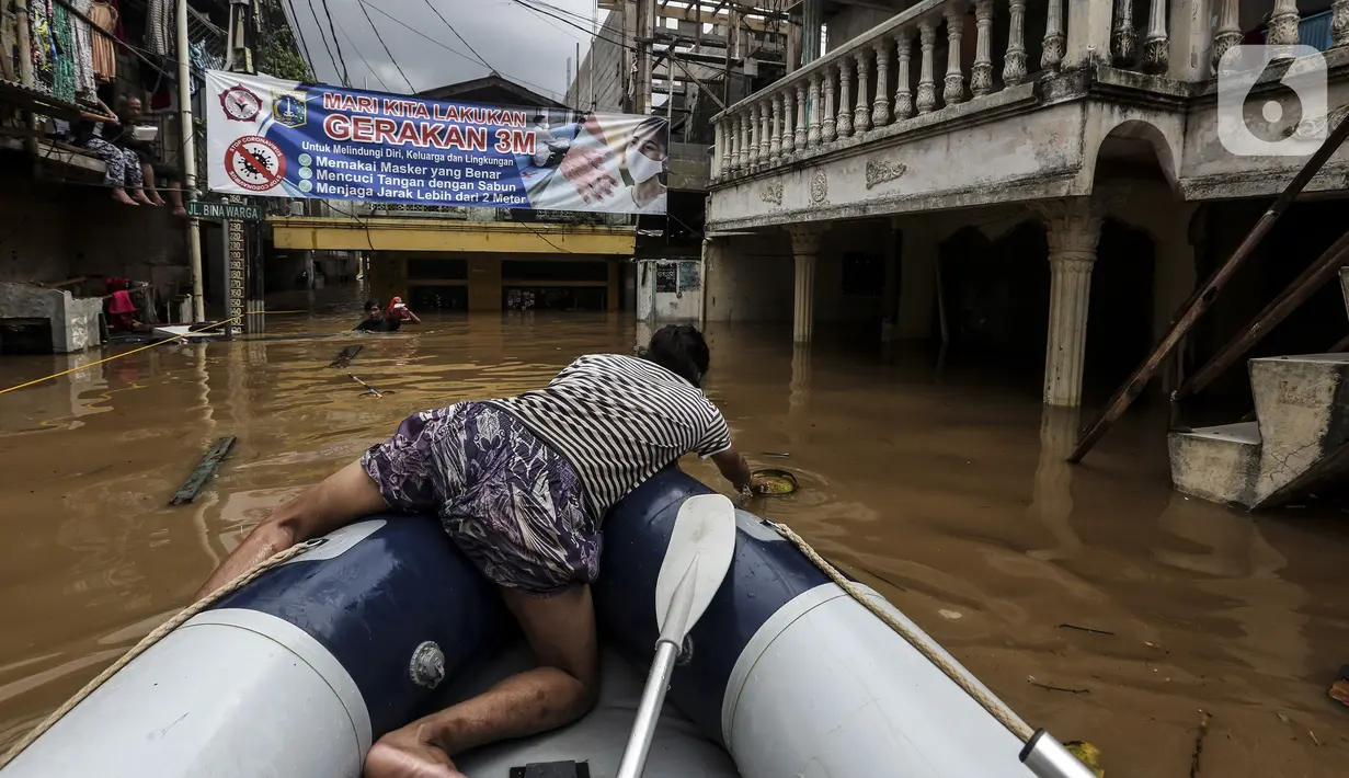 Warga mengambil barang dari air saat banjir melanda Jalan Bina Warga Rt 005/Rw 07 Kelurahan Rawa Jati, Jakarta, Senin (8/2/2021). Banjir setinggi 60-190 cm tersebut disebabkan oleh luapan air Sungai Ciliwung dan curah hujan Jakarta yang tinggi. (Liputan6.com/Johan Tallo)