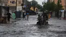 Serangan Israel juga memaksa sebagian besar warga untuk mengungsi ke tenda-tenda yang tidak memberikan perlindungan maksimal. Tampak dalam foto, warga Palestina berjalan di jalanan yang terendam banjir setelah hujan deras di Deir al-Balah, Jalur Gaza tengah, Selasa 25 November 2025. (AP Photo/Abdel Kareem Hana)