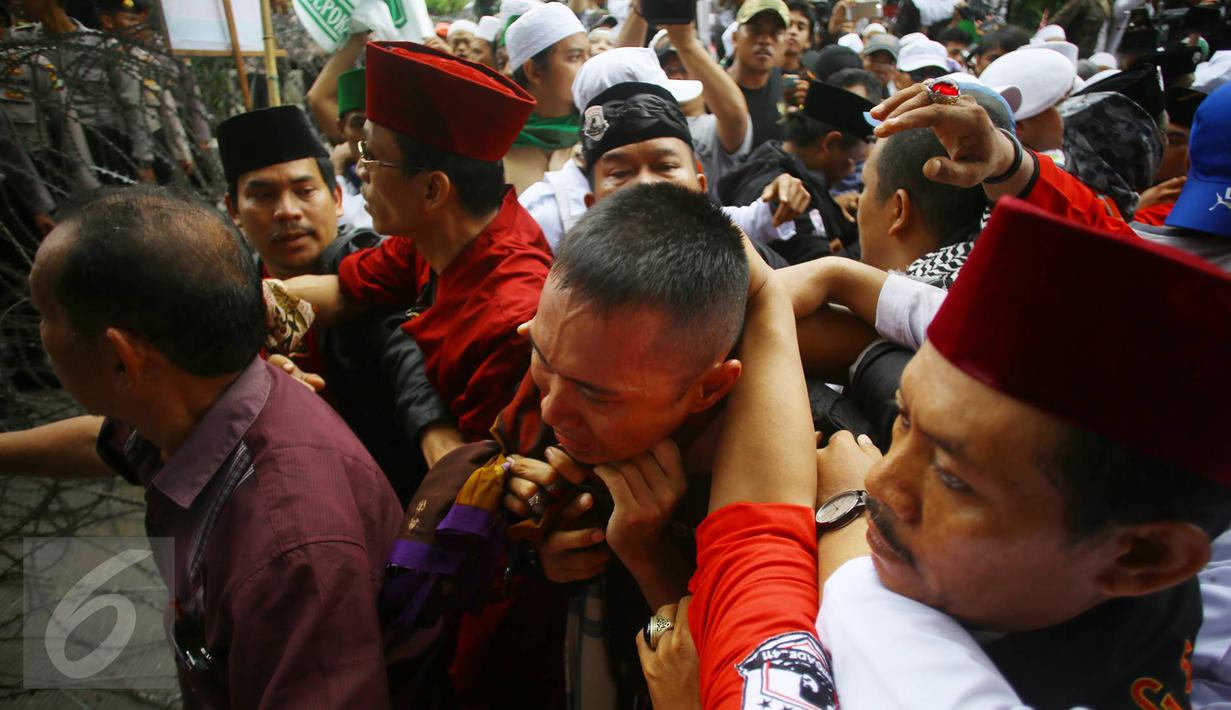 Ekspresi seorang pria yang diduga provokator diamankan dari amukan massa saat sidang kasus penistaan agama di Jakarta, Selasa (10/1). Sempat terjadi kericuhan akibat peristiwa tersebut. (Liputan6.com/Immanuel Antonius)