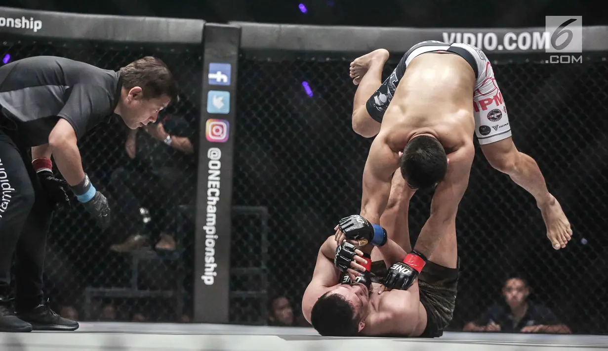 Dua petarung Indonesia Yohan Mulia Legowo (bawah) berusaha melakukan tendangan kepada Victorio Senduk (atas) pada laga One Championship di Jakarta, Sabtu (20/1). Pada laga tersebut Victorio Senduk menang atas Yohan Mulia. (Liputan6.com/Faizal Fanani)
