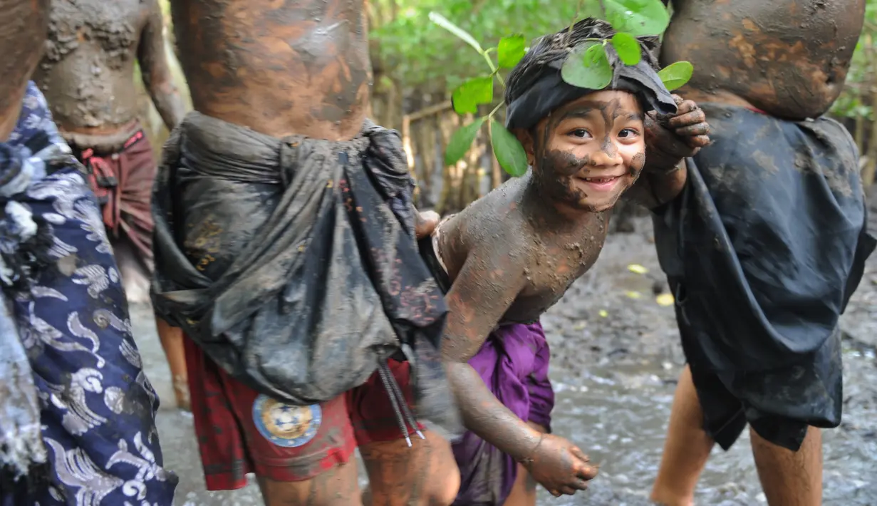 Ekspresi seorang anak dengan badan penuh lumpur saat mengikuti Mebuug-buugan di desa Kedonganan, Bali (18/3). Tradisi ini sarat dengan makna filosofi. Mebuug-buugan berasal dari kata Buug yang artinya tanah atau lumpur. (AFP/Sony Tumbelaka)