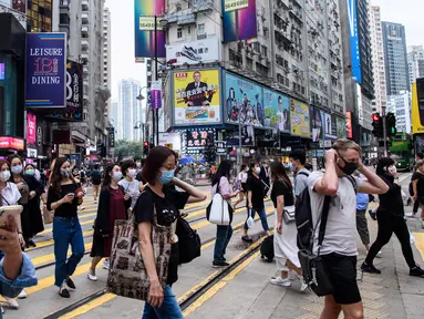 Pejalan kaki mengenakan masker sebagai tindakan pencegahan Covid-19 saat berjalan di Hong Kong (13/5/2020). Dua orang di Hong Kong dinyatakan positif Covid-19, mengakhiri perjalanan 24 hari tanpa kasus baru yang mulai melonggarkan peraturan jarak sosial. (AFP/Anthony Wallace)