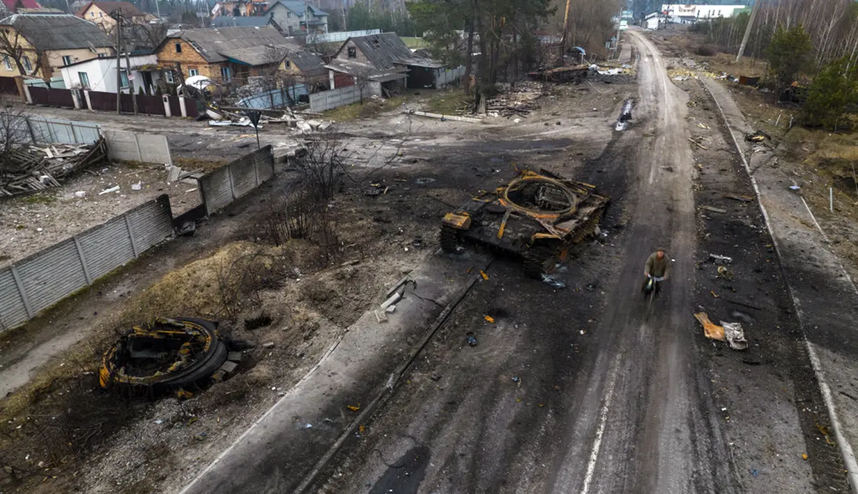 Oleksandr (81) mengendarai sepeda dekat tank Rusia yang hancur di pinggiran Kiev, Ukraina, 31 Maret 2022. Pasukan Rusia menembaki pinggiran Kota Kiev, dua hari setelah Kremlin mengumumkan akan secara signifikan mengurangi operasi dekat Ibu Kota dan Chernihiv. (AP Photo/Rodrigo Abd)