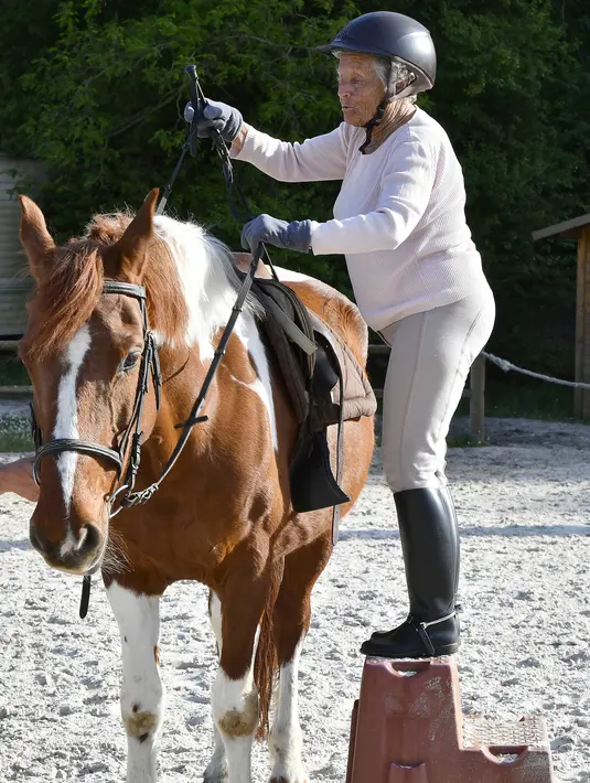 Nicole de Villeneuve (89) bersiap menaiki kuda selama latihan stabil berkuda di Arcachon (24/4). Nicole kembali berkuda pada September tahun lalu dan mengaku tidak memiliki kekuatan fisik yang sama seperti sebelumnya. (AFP Photo/Georges Gobet)