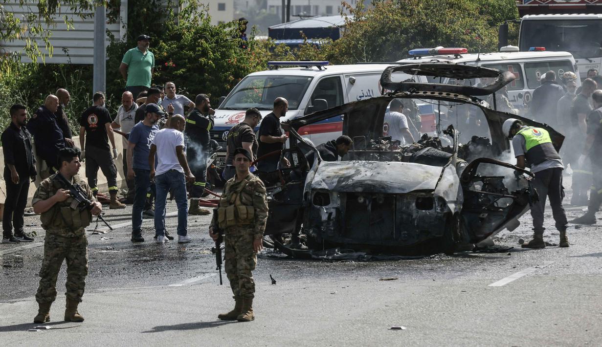 Petugas pertolongan pertama bekerja di sekitar kendaraan yang menjadi sasaran serangan pesawat tak berawak Israel di jalan raya dekat kota Jiyeh, Selatan Beirut, pada Rabu 13 Mei 2026. (MAHMOUD ZAYYAT/AFP)