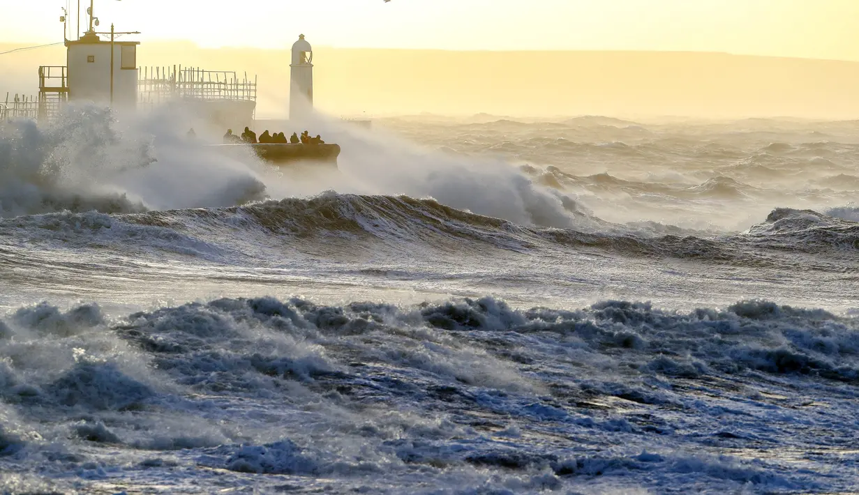 Ombak menghantam tembok laut saat Badai Eunice membawa angin kencang di Porthcawl, Wales, Inggris (18/2/2022). Inggris menempatkan tentara dalam keadaan siaga dan sekolah-sekolah ditutup ketika prakiraan cuaca mengeluarkan dua peringatan "cuaca merah". (AFP/Geoff Caddick)