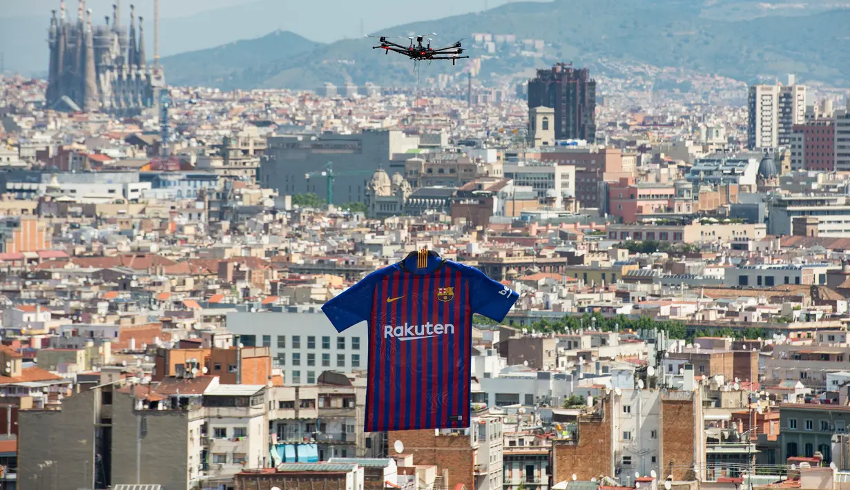 Sebuah drone menerbangkan jersey terbaru milik Barcelona untuk musim 2018/2019 saat diperkenalkan kepada publik di Montjuic Swimming Pool, 19 Mei 2018. Motif seragam Blaugrana sendiri masih menggunakan warna andalannya, merah dan biru. (AFP/Josep LAGO)