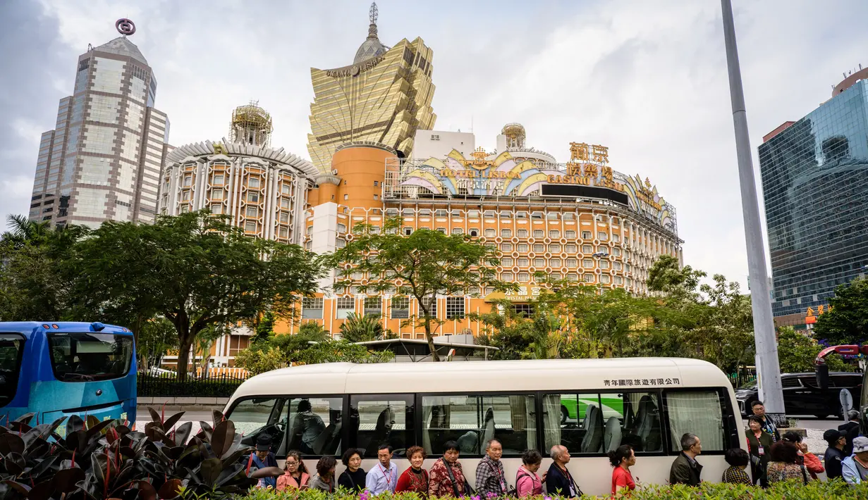 Wisatawan antre untuk menaiki bus dengan latar belakang resor kasino Grand Lisboa (tengah) di Macau, 5 Maret 2019. Hampir setengah PDB Macau atau sekitar 45 miliar dolar AS bersumber dari perjudian. (Anthony Wallace/AFP)