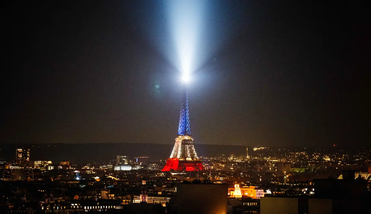 Foto ini menunjukkan Menara Eiffel yang diterangi dengan warna bendera nasional Prancis saat peringatan ke-10 serangan teroris Paris yang terjadi pada 2015, di Paris, pada 12 November 2025. Prancis memperingati satu dekade tragedi berdarah pada 13 November 2015. (Dimitar DILKOFF/AFP)
