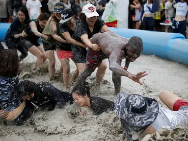 Sejumlah turis mengikuti sebuah permainan dalam Festival lumpur Boryeong di pantai Daecheon, Boryeong, Korea Selatan, (15/7). Festival lumpur Boryeong selalu mengadakan berbagai perlombaan yang menggunakan arena berlumpur. ( REUTERS/Kim Hong-Ji)