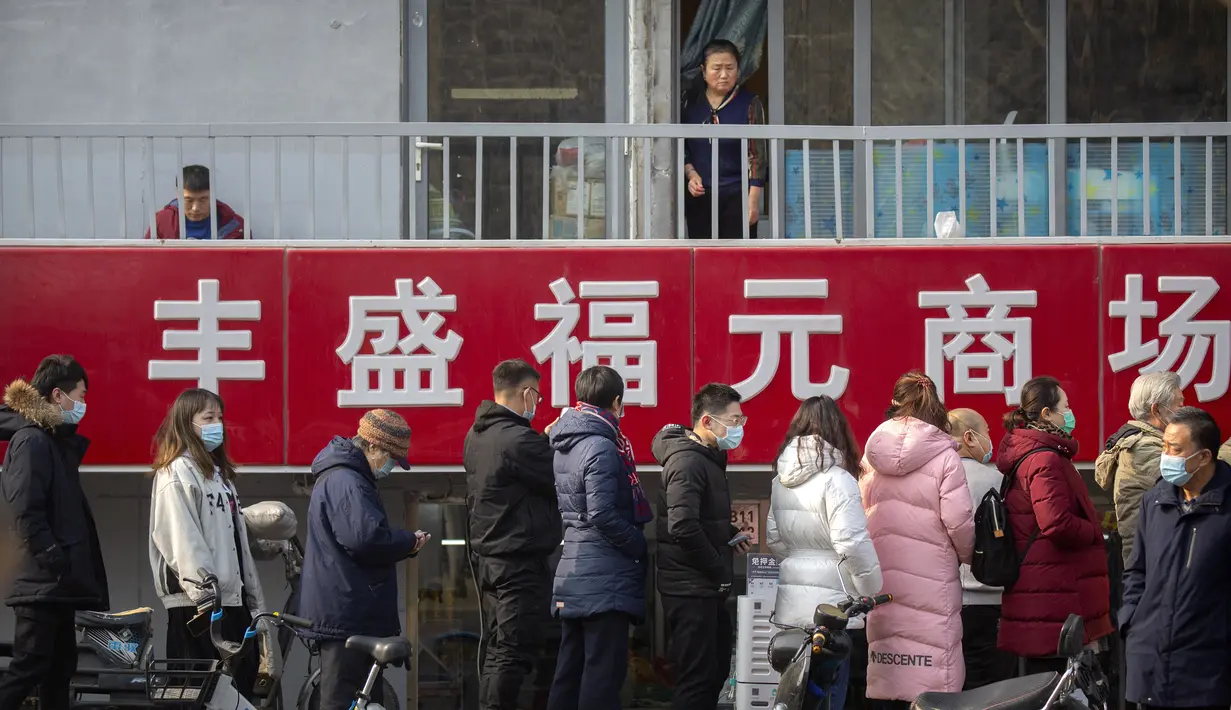 Seorang wanita melihat orang-orang yang berbaris untuk pengujian massal COVID-19 di Beijing, China, Jumat (22/1/2021). Beijing memerintahkan pengujian COVID-19 untuk sekitar dua juta orang menyusul kasus baru. (AP Photo/Mark Schiefelbein)