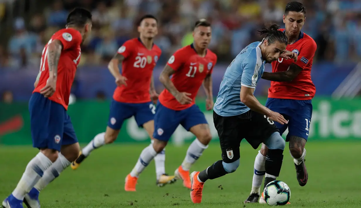 Bek timnas Uruguay, Martin Caceres menggiring bola dibayangi pemain Chile,  Erick Pulgar pada laga terakhir grup C Copa America 2019 di stadion Maracana, Senin (24/6/2019). Uruguay berhasil melaju ke perempatfinal dengan status juara Grup C usai mengalahkan Chile 1-0. (AP/Silvia Izquierdo)